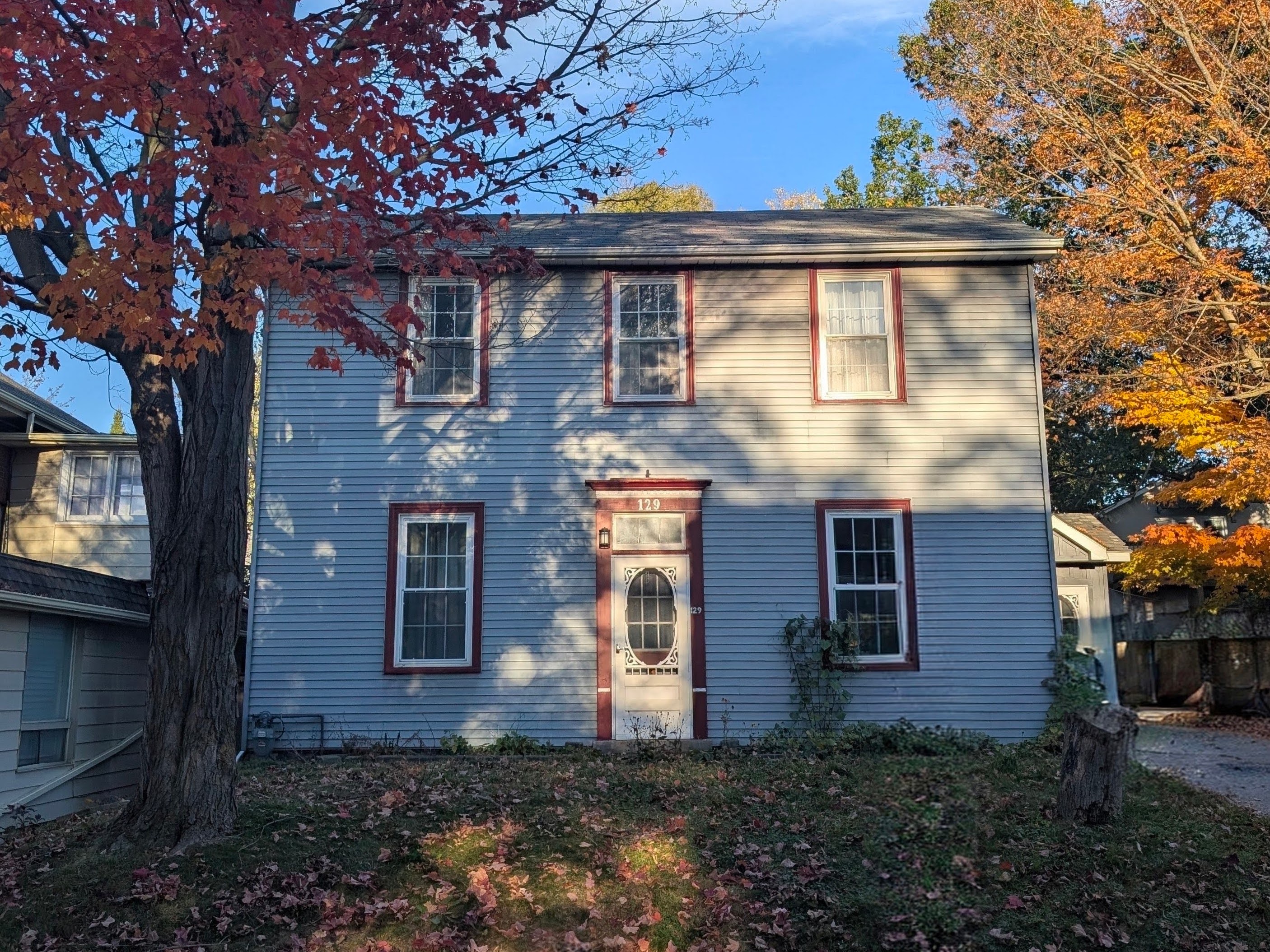 Straight-on view of the two-storey house at 129 Raglan Street, framed by autumn foliage
