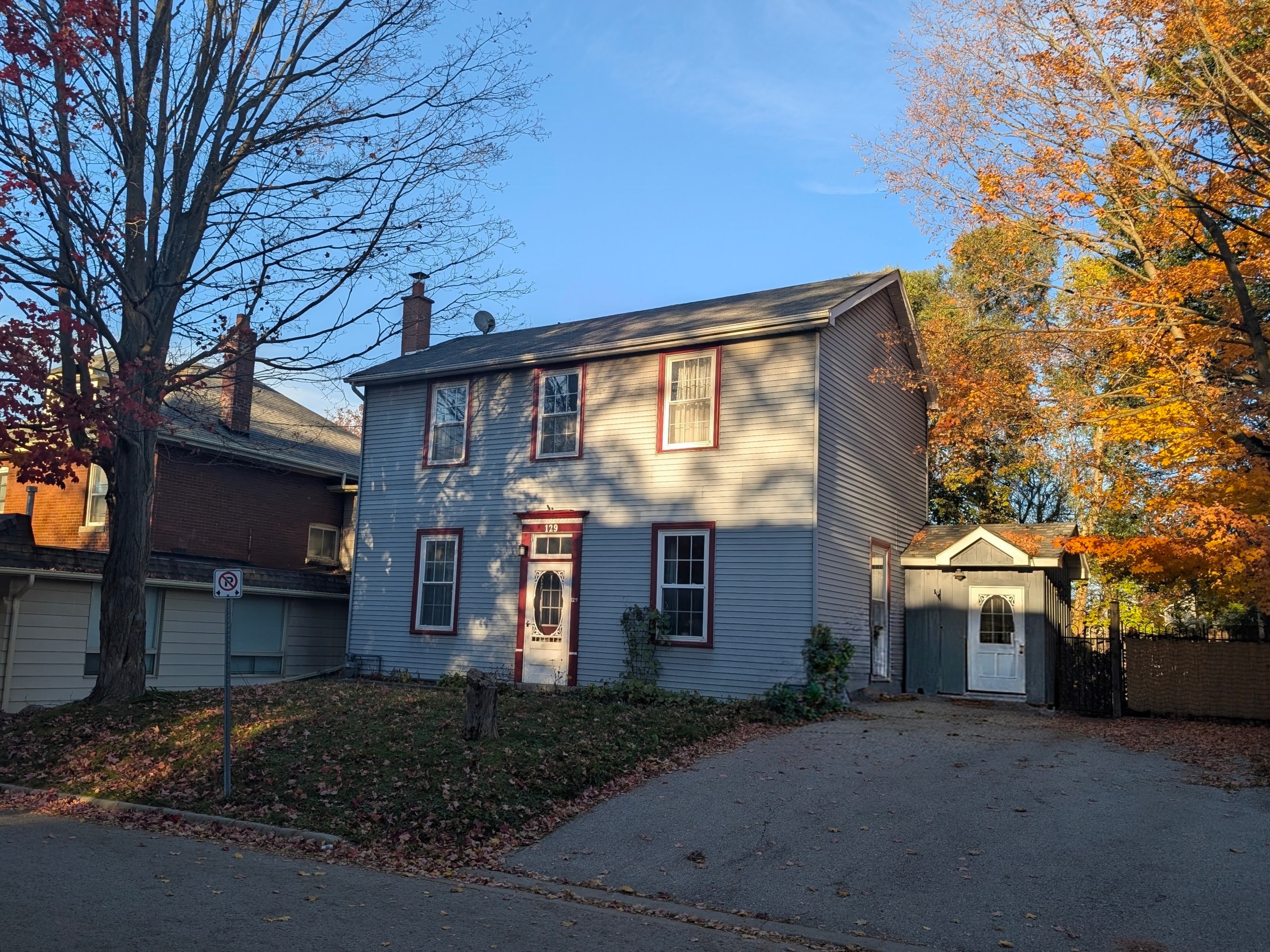 129 Raglan Street from the street, showing the two-storey house, driveway, neighbouring building and autumn trees