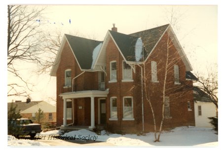 Historic winter photograph of the red-brick Joseph Lundy House showing its gables, bay windows and entrance