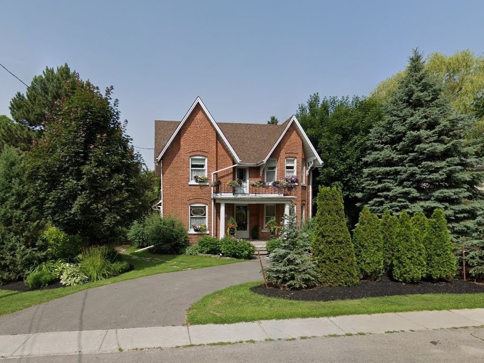 The red-brick Joseph Lundy House at 16874 Bayview Avenue, with two steep Queen Anne gables, a front porch and landscaped grounds