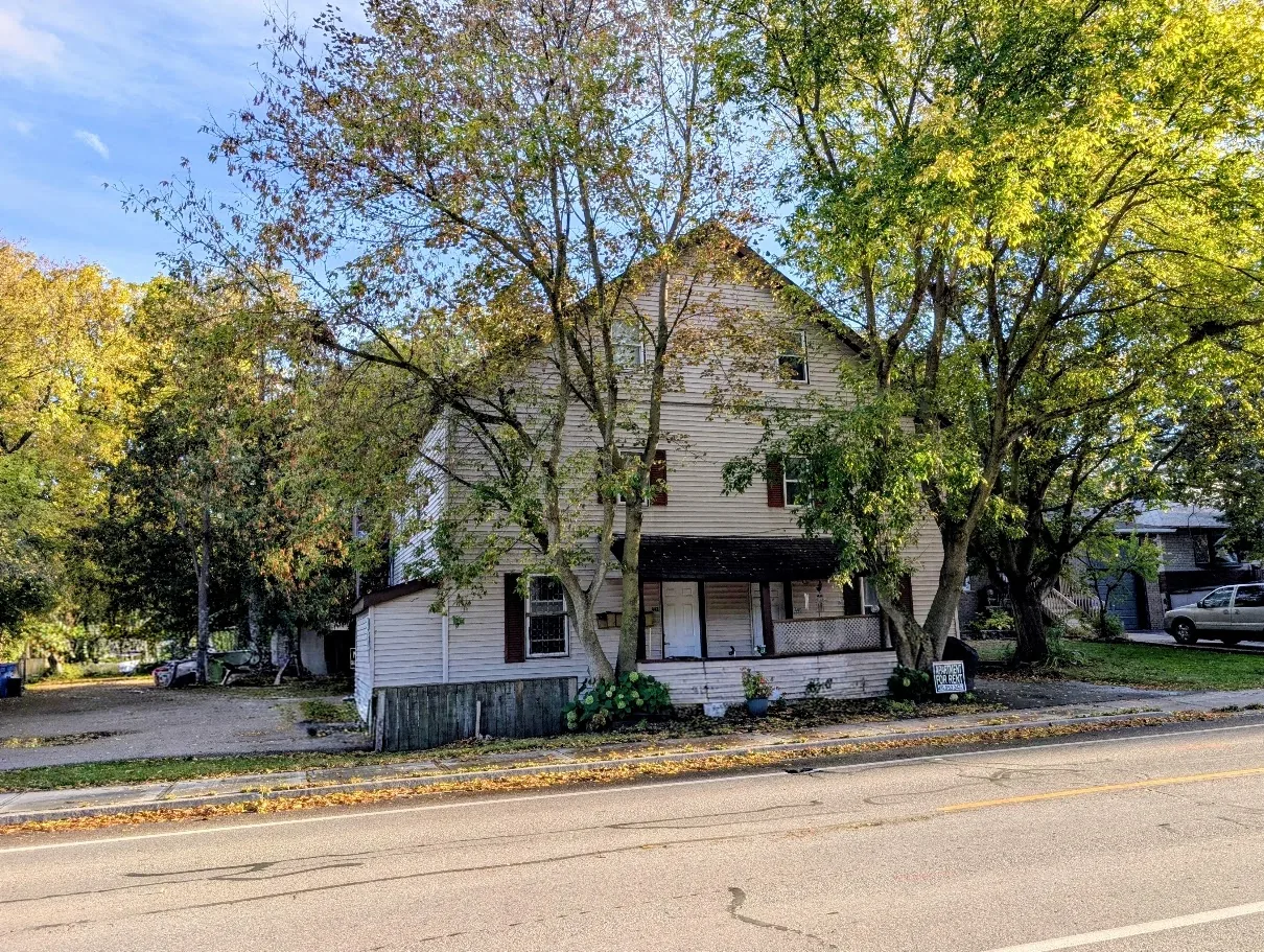 440–442 Eagle Street in Newmarket, photographed in autumn, with its pale clapboard exterior and broad gable visible among the roadside trees